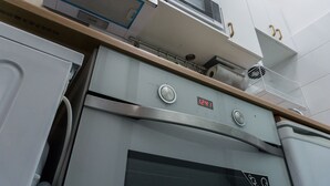 Una cocina con horno empotrado, microondas y un reloj digital que marca las 12:41.