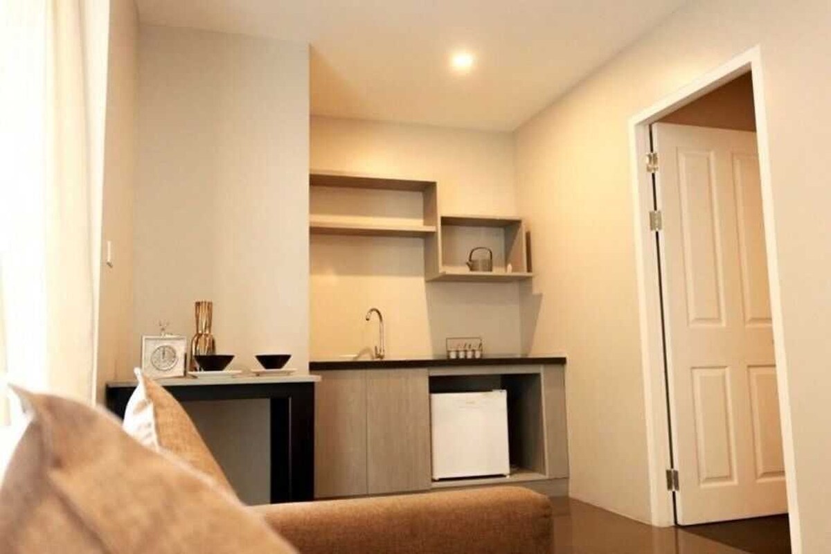 A compact kitchen with a sink, cabinets, and a refrigerator.