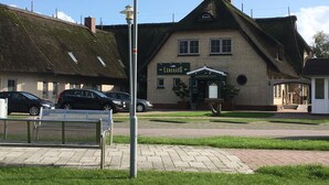 Een traditioneel gebouw met een rieten dak en een bord met daarop 'Landhaus Restaurant & Cafe'.