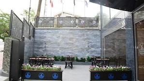 An outdoor seating area with tables and chairs, a decorative fence, and a stone wall. - Radar Otel (Istanbul)