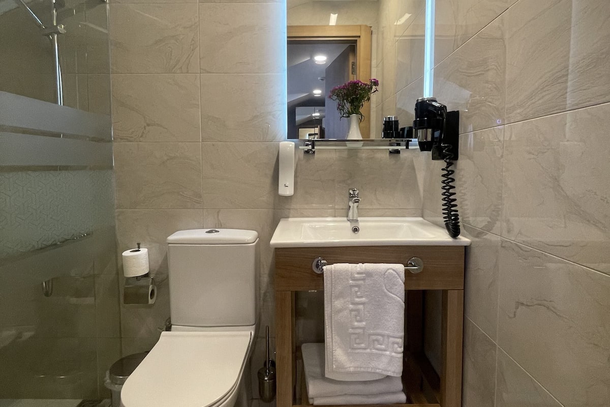 Un baño moderno con inodoro, lavamanos y cabina de ducha de vidrio.