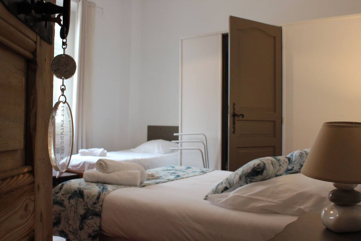 Een hotelkamer met een bed, een nachtkastje met een lamp, een deur en een raam.
