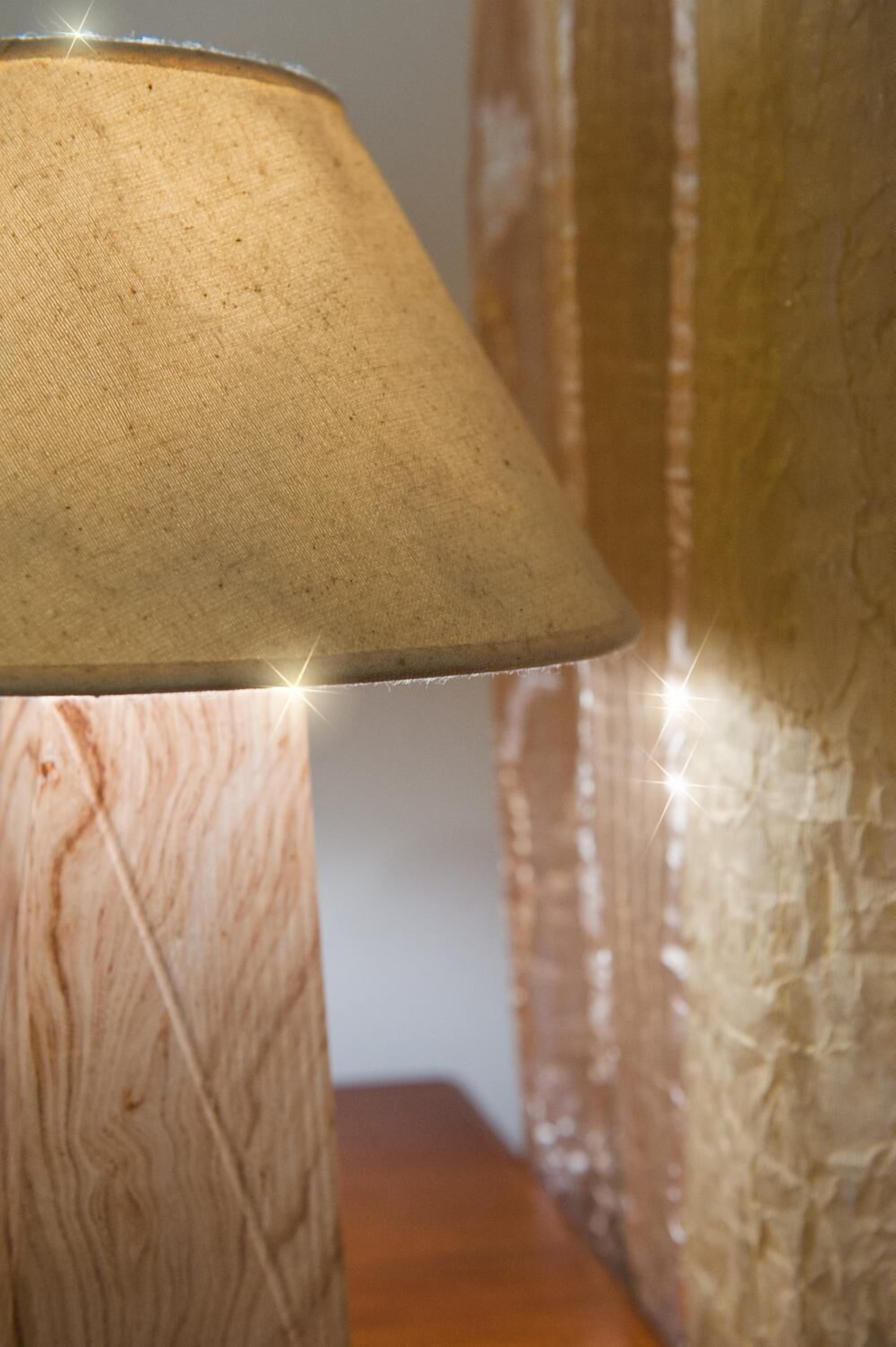 Primer plano de una lámpara con pantalla de tela y base de madera.