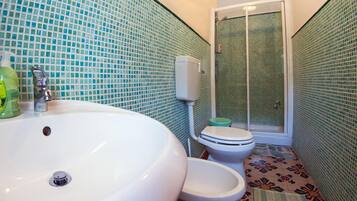 A bathroom with a large white sink, a toilet, and a shower enclosure.
