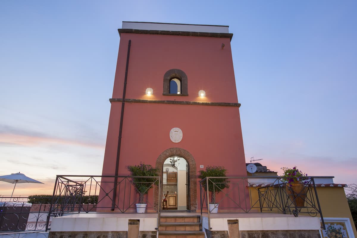 A pink tower with a balcony and steps leading to the entrance.