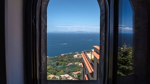 A view through a window with an arched frame, overlooking a coastal area with buildings and greenery. - Torre Elisabetta (Massa Lubrense)