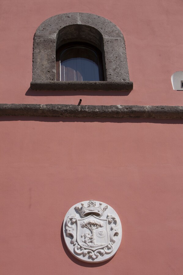 Fachada de edifício com janela de pedra e brasão.