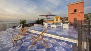 A rooftop terrace with lounge chairs, a table, and a large umbrella. - Torre Elisabetta (Massa Lubrense)