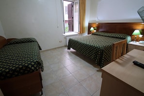A hotel room with two beds, a wooden headboard, a small table, and a window with curtains. - Hotel Rosetta (Rome)