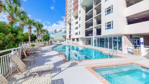 Un área de piscina con sillones de descanso y un edificio con balcones.