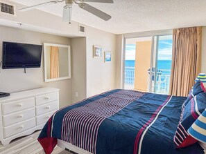 Habitación de hotel con cama, televisión, cómoda y balcón con vistas.