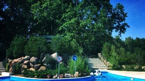 A swimming pool surrounded by rocks and trees, with a no swimming sign and a directional sign. - Ferienpark Canow (Wustrow)