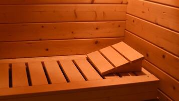 Eine Holzsauna mit einer Sitzbank und einem kleinen Holzklotz.