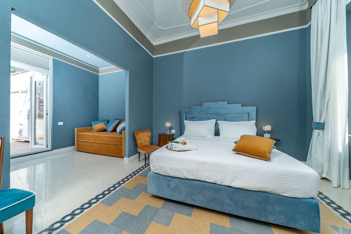A modern bedroom with a large bed, a sofa, and a chair.