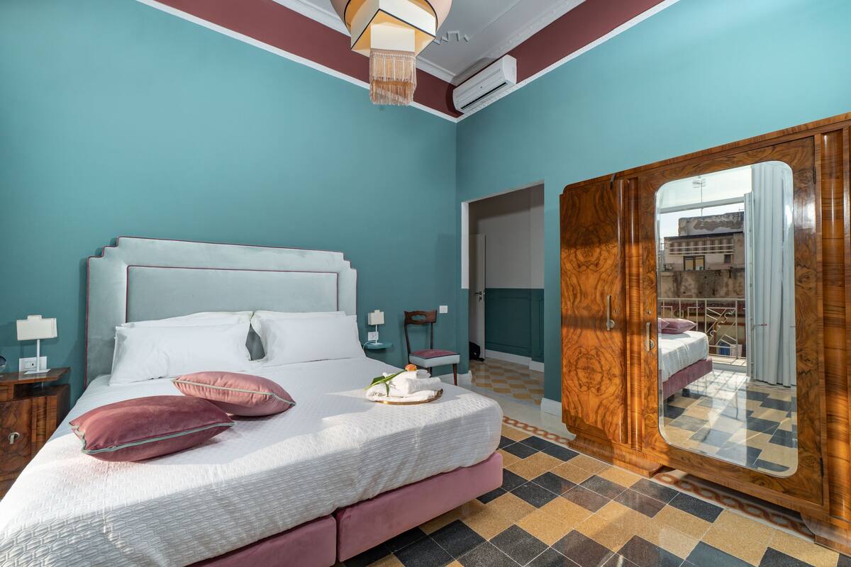 A bedroom with a bed, nightstands, a dresser, and a view through a door.