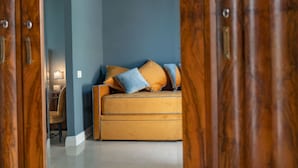 A room with a sofa against a blue wall, a wooden door, and a lamp in the corner. - Il Fiore D'Oro Luxury (Naples)