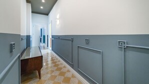 A hallway with a checkered floor, grey walls, and a wooden bench. - Il Fiore D'Oro Luxury (Naples)