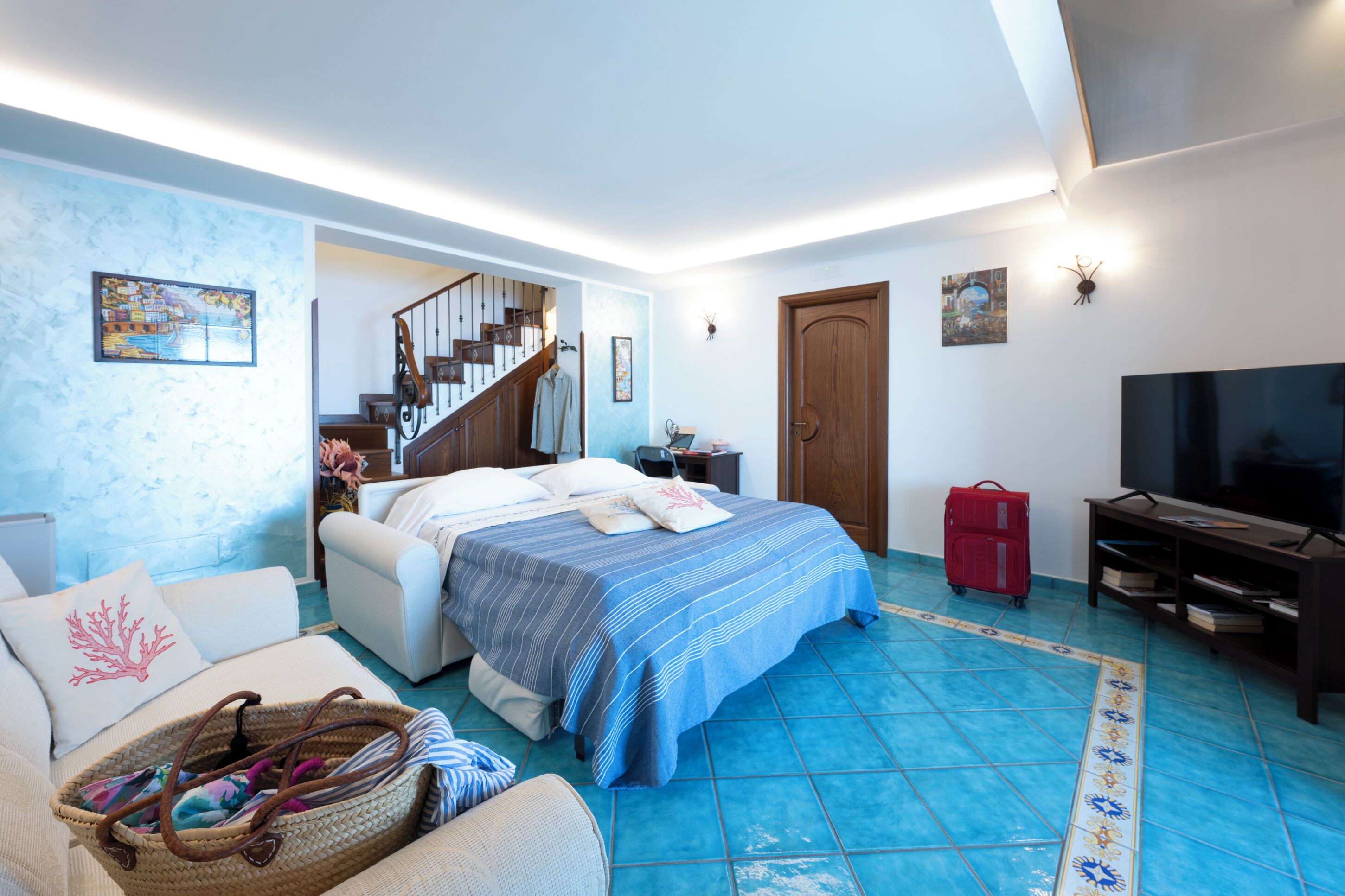 Una camera da letto con un letto, una televisione, una valigia e una scala.