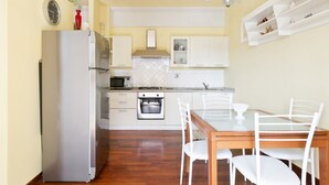 Una cucina con mobili bianchi, un frigorifero, un fornello e un tavolo da pranzo con sedie.