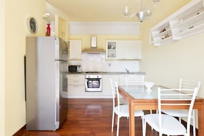A kitchen with white cabinets, a refrigerator, a stove, and a dining table with chairs.