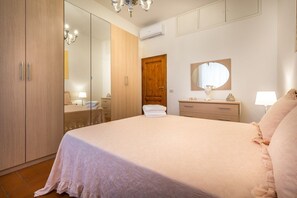 A bedroom with a bed, a wardrobe, a mirror, and a door.