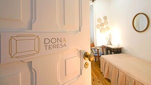 A room with a bed, a desk, and a chair. There is a sign on the door that reads "DONA TERESA". - 5 Bedroom Family  Apartment (Lisboa)