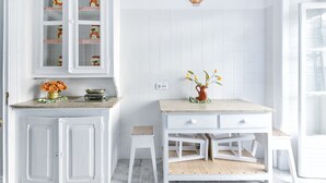 A kitchen with white cabinetry, a countertop with a vase of flowers, and a small stool. - 5 Bedroom Family  Apartment (Lisboa)
