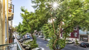 A street view with parked cars, trees, and buildings. - 5 Bedroom Family  Apartment (Lisboa)