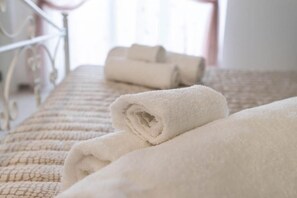 A neatly made bed with rolled white towels and a patterned bedspread. - Il Tulipano Verde B&B (Putignano)