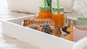 A tray with pastries, a drink, and a flower on a bed with white towels. - Il Tulipano Verde B&B (Putignano)