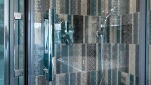 A shower with a glass door and a patterned tile wall. - Il Tulipano Verde B&B (Putignano)