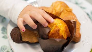 Una mano sosteniendo un muffin en un vaso de papel sobre un plato.