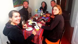 A group of people seated around a table with various food items and drinks. - the heart of cusco  (Cusco)