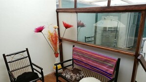 A small, cozy room with a wooden bench, a cushioned chair, and a colorful woven bench. - the heart of cusco  (Cusco)