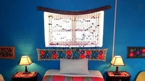 A room with a bed, two bedside tables with lamps, a window with decorative grills, and wall art. - the heart of cusco  (Cusco)