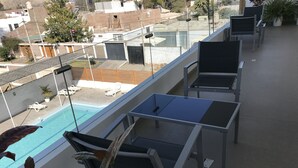Une terrasse sur le toit avec une piscine, des chaises longues et une table.