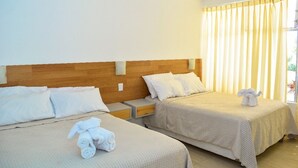 Une chambre d’hôtel avec deux lits, chacun doté d’une tête de lit en bois, de draps blancs et d’une serviette posée sur le lit.