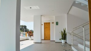 Un hall d’hôtel moderne avec une porte en bois, un escalier et des plantes en pot.