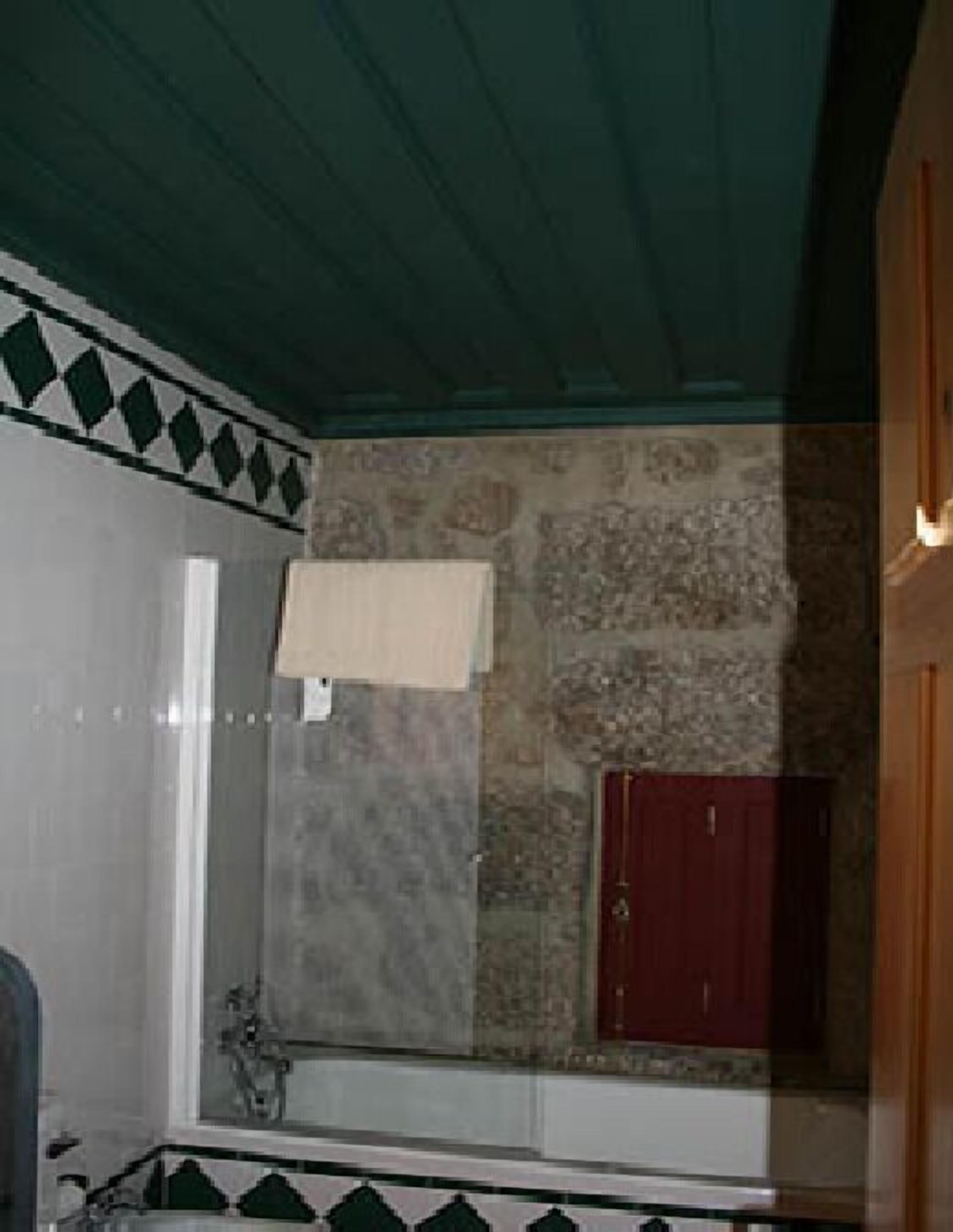 A bathroom with a shower, a mirror, and a red cabinet.