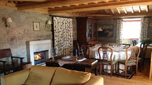 Ein gemütliches Wohnzimmer mit Kamin, Holzmöbeln und einem Essbereich mit gedecktem Tisch.