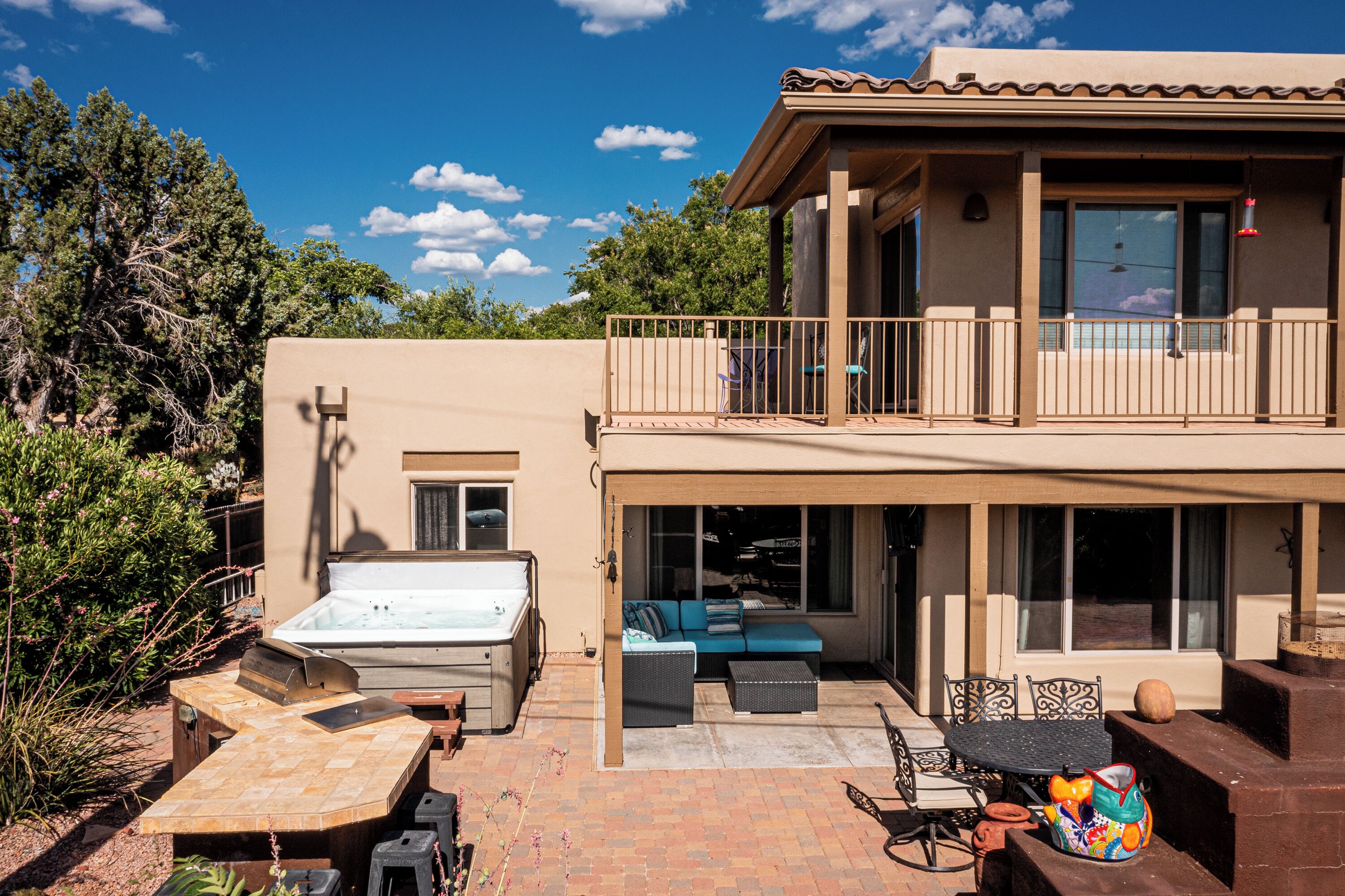 A two-story house with a balcony, a hot tub, and outdoor seating.