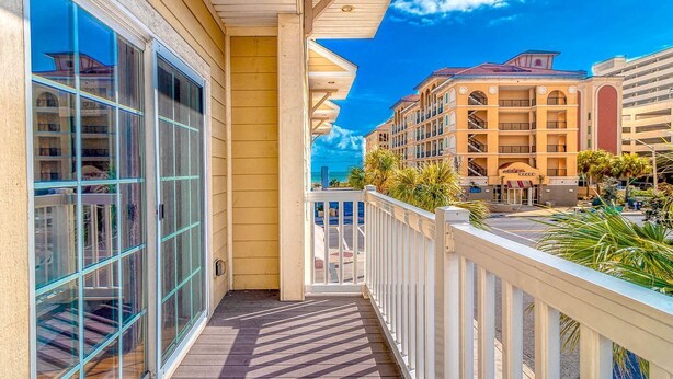 A balcony with a view of a hotel building and palm trees.