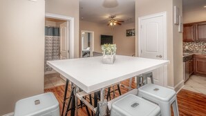 A modern kitchen with wooden cabinets, a white countertop, and a ceiling fan.