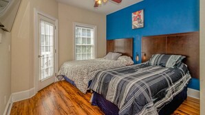 A bedroom with two beds, a ceiling fan, and a blue accent wall.