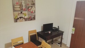A small room with a wooden desk, a television, and two chairs.
