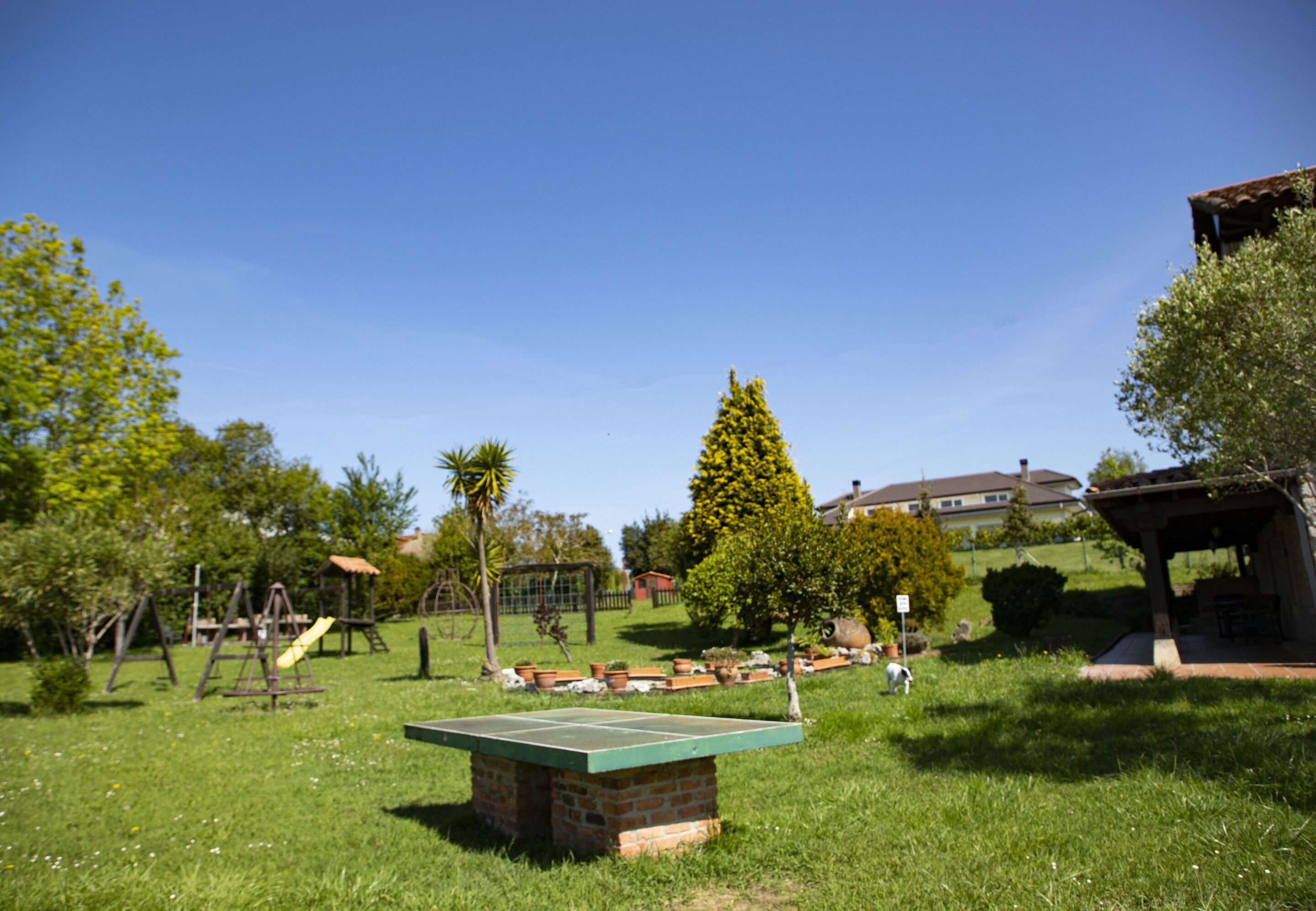Un parque con mesa de ping pong, juegos infantiles y un pabellón.