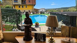 Une vue depuis une fenêtre donnant sur une piscine, une statue, une lampe et un calendrier.