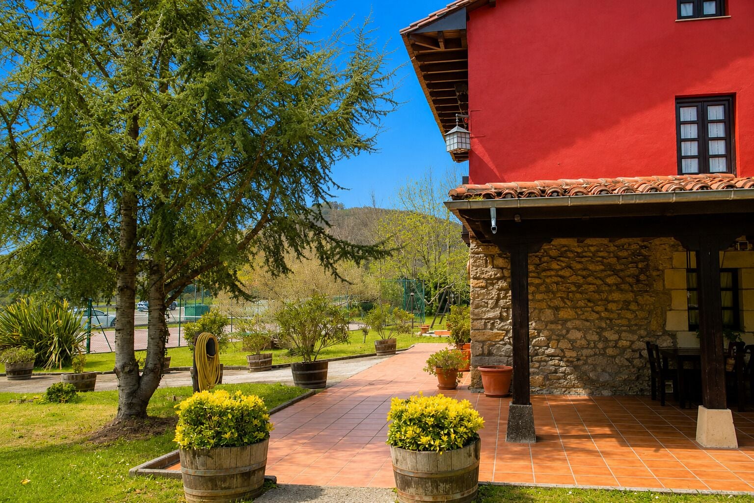 A red building with a stone exterior, a tiled patio, and potted plants.