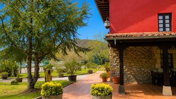 A red building with a stone exterior, a tiled patio, and potted plants.