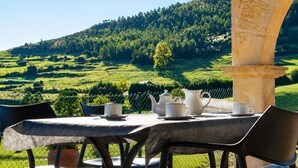 Une table dressée à l’extérieur, avec vue sur une colline verdoyante.